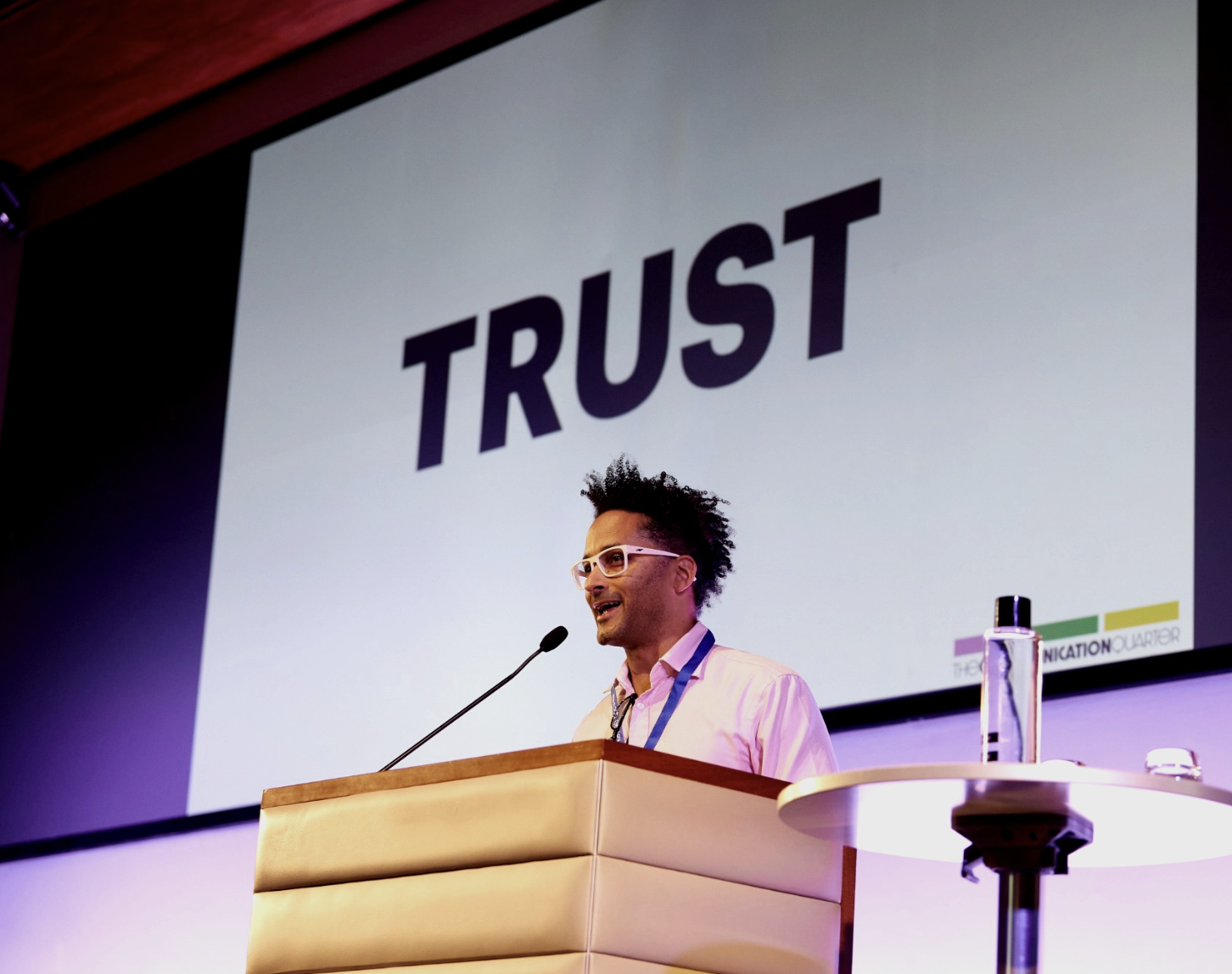 Jason Piper speaking on stage with the word TRUST displayed behind him